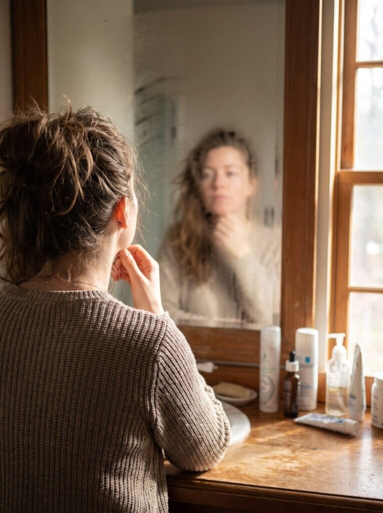 Woman looking at her reflection in a bathroom mirror